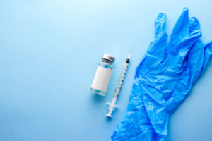 Picture of a vial of liquid, a syringe, and a pair of surgical gloves.