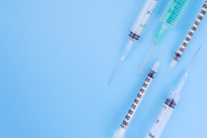 Picture of five different-sized syringes on a blue background.