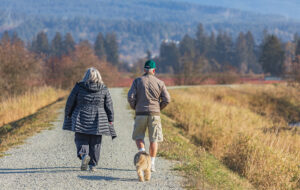 Senior active couple walking with their dog in the park